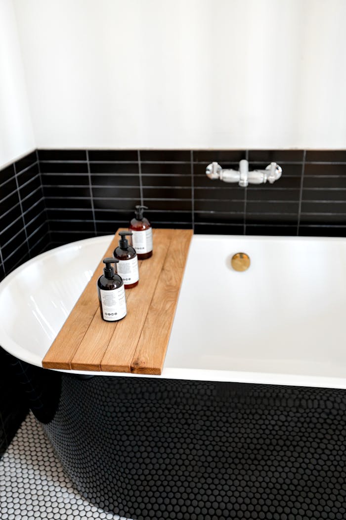 Stylish bathroom with black and white tiles, tub, and bath products.