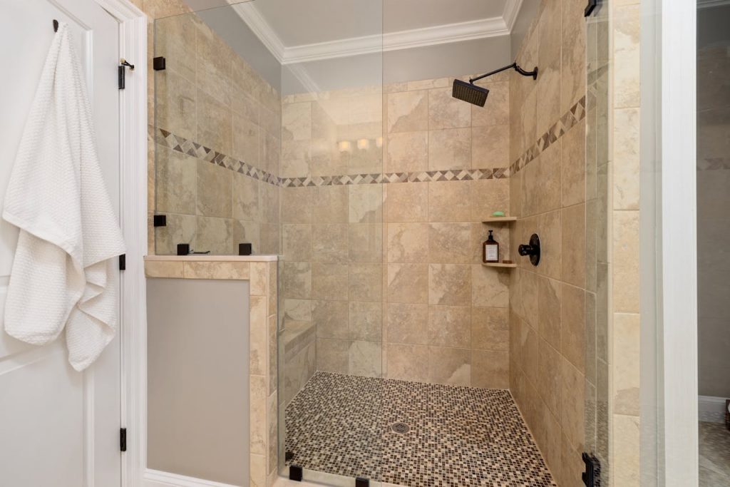 Elegant tiled shower interior with glass door and modern fixtures.