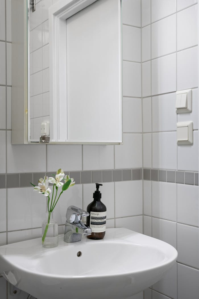 Contemporary bathroom with white tiles and minimalist design featuring a sleek sink and faucet.