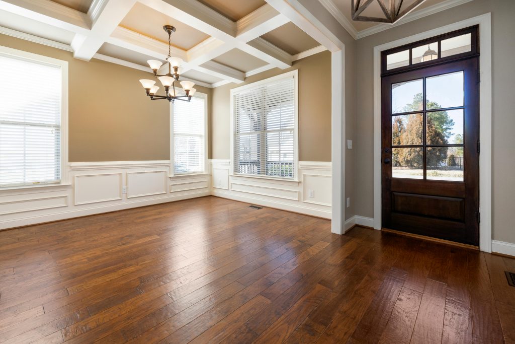 Engineered Hardwood Spacious empty living room with wooden flooring, large windows, and ceiling lights.